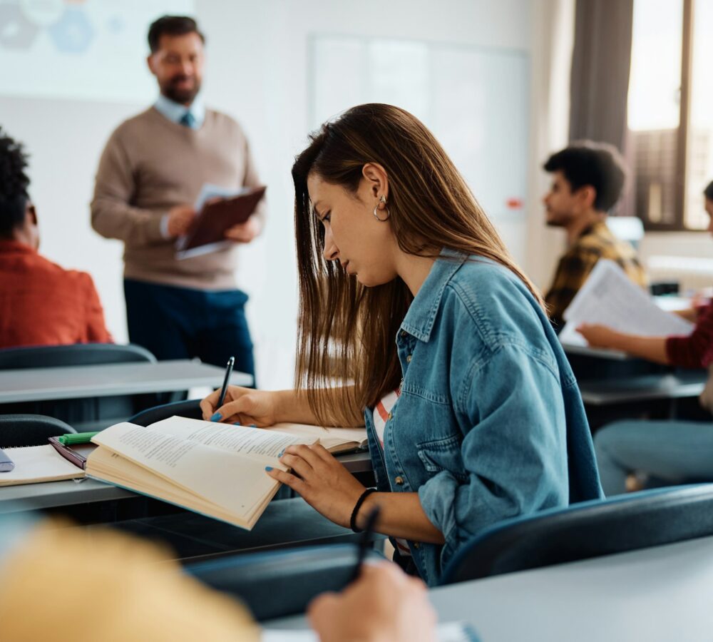female student taking notes during a class at the university